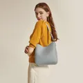 Minimalist light blue leather bucket shoulder bag worn by model in a professional studio setting - Blue