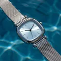Close-up of a silver square lady watch with mesh strap on rippling blue water background - Light Blue Dial