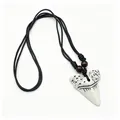 Detailed macro view of a tribal faux shark tooth resin pendant with black cord and wooden beads - White