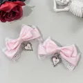 Close-up detail of pink lace bow hair clips with heart cross pendant in gothic style. - Pink