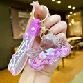 Gros plan d'un porte-clés moto violet de rêve avec du sable liquide coloré scintillant - Moto En Corde Florale Violette Et Flocon De Neige Lumineux