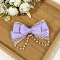 Detailed view of lavender satin bow hair clip with lace trim and pearl tassels - Purple