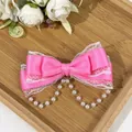 Detail view of a pink satin bow hair clip with lace and pearl tassels - Rose Red
