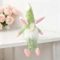 Plush Easter gnome doll with long striped legs and bunny ears sitting on a desk edge. - Green