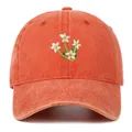 Detailopname van delicaat wit bloemborduursel op een vintage gewassen oranje baseballpet. - Eén maat / Regular Fit / Oranje