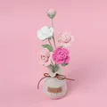Handmade crochet rose flower arrangement in a beige knitted bag vase on pink background. - 4-Head Gradient Pink Miniature Rose Potted Plant (Yarn Vase Base)