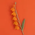 Close-up of a handcrafted orange crochet Lily of the Valley flower with fine yarn texture - Orange