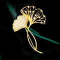 Eleganter goldener Ginkgo-Blatt-Anstecker mit Zirkonia auf dunkelgrüner Seide. - B124