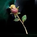 Elegante broche de rosa con circonitas rojas y verdes y un acabado dorado de lujo. - B039