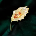 Lujoso broche de hoja en acabado dorado con piedra naranja talla pera y circonitas CZ - B467