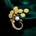 Elegante broche de pavo real con cristales amarillos y perla blanca en baño de oro - B288