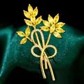 Elegante broche floral dorado con circonitas amarillas sobre fondo de raso verde oscuro - B536