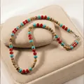 Bohemian necklace with coconut shell, turquoise, and red beads on a beige velvet stand. - ZJ16359