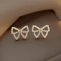 Elegant butterfly-shaped stud earrings made of small white pearls with gold-tone center. - 64# Hollow Pearl Bow Earrings