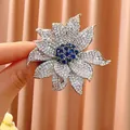 Eleganter silberfarbener Blumen-Brosche mit vollem Zirkonia und blauem Mittelstein. - B1743