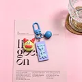 Close-up of a cute green resin monster keychain with a purple 'Cola' tag. - Cola