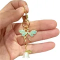 Gold dragonfly metal keychain with light blue wings and a delicate white bell flower charm. - Dragonfly White Lily Of The Valley