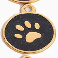 Close-up of circular pet ID tag with golden paw print on black glitter background - Black / 28mm