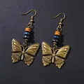 Boucles d'oreilles vintage papillon en bronze avec perles en bois sur fond noir - Boucles d'oreilles papillon dorées en strass