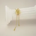 Detailed view of golden cowboy hat pendant necklace with textured brim on white pillar - Gold