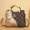 Monogram printed brown tote bag featuring golden hardware and decorative pearl charm - Gold