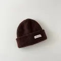 Close-up of brown knitted baby beanie with white original label - Kids / Brown