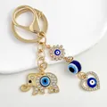 Gold Evil Eye keychain featuring rhinestone elephant and heart charms on white background - Gold Elephant Heart Sun Motif (6362)