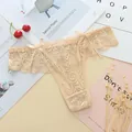 Close-up of beige lace thong with bow details and delicate floral jacquard patterns. - One Size / Apricot