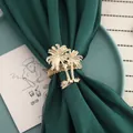 Macro detail of an elegant golden palm tree napkin ring on premium dark green fabric - Spring Ring Coconut Tree / Gold
