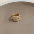 Primo piano di un ear cuff dorato a più strati con zirconi bianchi scintillanti - Singolo / Oro