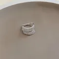 Dettaglio di un elegante ear cuff multistrato in argento e zirconi per orecchie non forate - Singolo / Argento