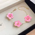 Detailed view of pink enamel flower charm bracelet with gold-tone adjustable chain - Bracelet / Pink