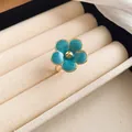 Macro detail view showing a turquoise blue enamel flower ring displayed in a cream jewelry box - Ring / Blue