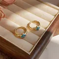 Macro detail view of luxury gold hoop earrings featuring a turquoise four-leaf clover - Flower Hoop / Gold-Blue