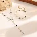 Detailed macro view of titanium steel Y-necklace and bracelet set with black beads - Tassel Necklace + Bracelet Set (E108) / Gold