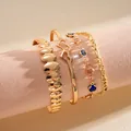 Dettaglio ravvicinato di un set di 4 bracciali in metallo dorato con cuori e pietre - Four-Piece Set / Oro