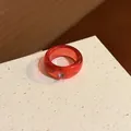 Detailed view of a minimalist translucent red resin ring with a small purple gemstone - Red
