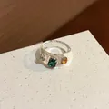 Nahaufnahme eines klaren Harzrings mit eingebetteten grünen und orangefarbenen Steinen - Transparent Grüner Strass / Weiß-Grün