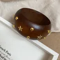 Dettaglio raffinato di un bracciale in resina marmorizzata con borchie a stella dorate - Stile 50 - Caffè Oro