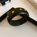 Dettaglio macro del bracciale in resina marmorizzata verde scuro con borchie oro - Stile Vintage di Nicchia / Borchia Oro Verde Scuro