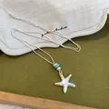 Gros plan du pendentif collier étoile de mer en argent mat avec détails de perles bleues - Style 1 Étoiles / Argent
