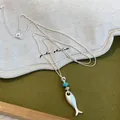 Gros plan détaillé d'un collier pendentif poisson en argent mat avec petite perle bleue décorée - 2# Style Poisson / Argent