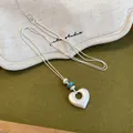 Détail d'un collier pendentif cœur en argent mat avec perles turquoise sur tissu - 7# Style Cœur Plissé