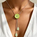 Detail van een mintgroene knoop-Y-ketting met druppelvormige hangers op een model. - Y-Kwastje Stijl / Groen