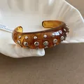 Amber resin open cuff bracelet with silver studs in a shell ceramic dish - Style 56