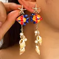 Vue détaillée de boucles d'oreilles poisson tropical en céramique avec glands de coquillages - Gland de Poisson en Céramique Dorée (6831)