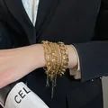 Dettaglio ravvicinato di bracciali a catena in metallo dorato a strati sul polso di una persona. - 4# Bracciale / Set di 4 / Oro
