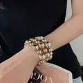 Primo piano di un elegante bracciale a strati con perle metalliche oro e argento. - Style 14 Bracelet / Set di 3 / Oro e Argento