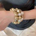 Primo piano di un set di braccialetti a strati con perle bianche e perline d'oro testurizzate - Style 17 Bracelet / Set di 3 / Oro