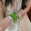 Dettaglio di bracciali rigidi geometrici in metallo e bracciale di perline verdi sul polso. - Stile 40 / Set da 6 Pezzi / Argento, Verde